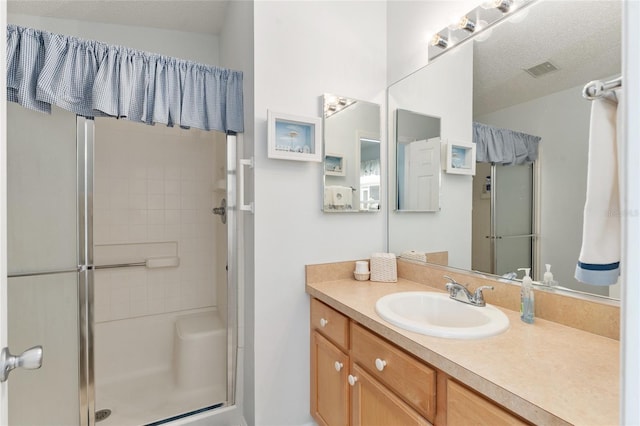 bathroom with an enclosed shower, vanity, and a textured ceiling