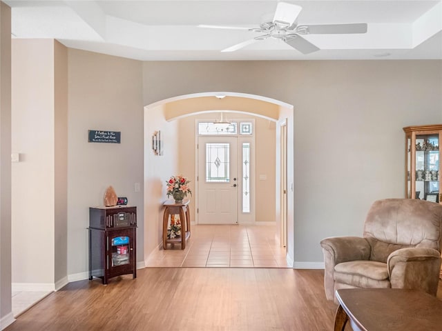 foyer featuring ceiling fan, a raised ceiling, and light wood-type flooring