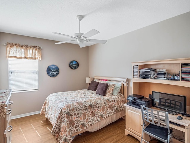 bedroom featuring ceiling fan, light hardwood / wood-style floors, and a textured ceiling