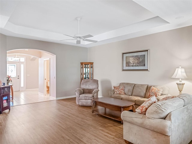 living room featuring a tray ceiling, light hardwood / wood-style flooring, and ceiling fan