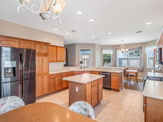 kitchen featuring kitchen peninsula, appliances with stainless steel finishes, decorative light fixtures, an inviting chandelier, and a kitchen island