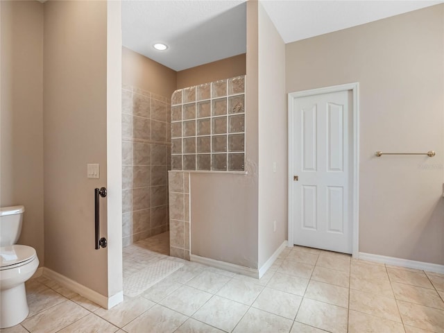 bathroom with tile patterned flooring, toilet, and a tile shower