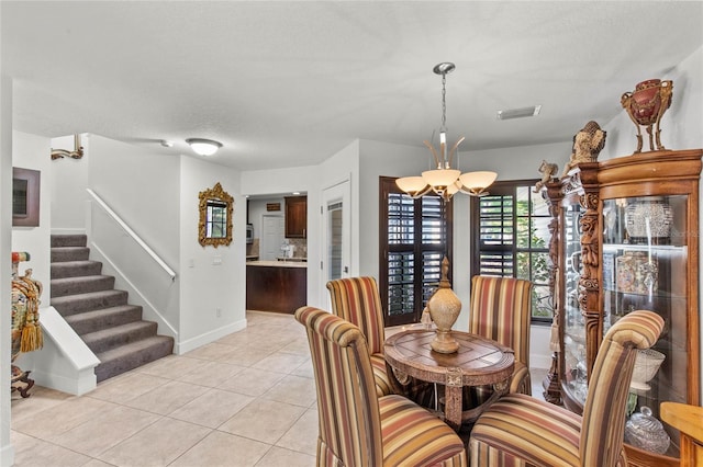 dining room featuring a textured ceiling, an inviting chandelier, and light tile patterned floors