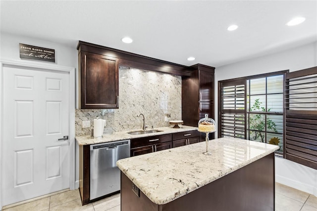 kitchen with stainless steel dishwasher, sink, a center island, and light stone countertops