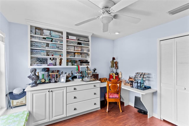 office space with ceiling fan, built in desk, and dark hardwood / wood-style flooring