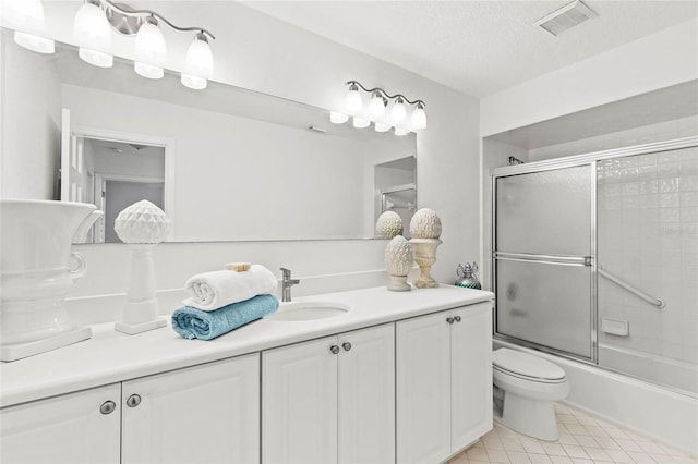 full bathroom featuring vanity, a textured ceiling, bath / shower combo with glass door, and toilet