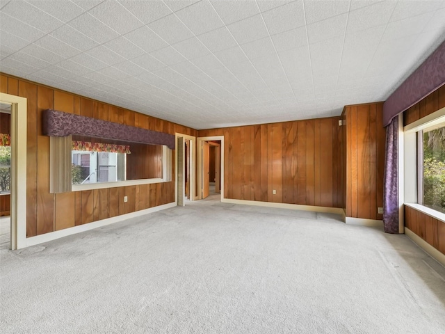 carpeted spare room featuring wood walls