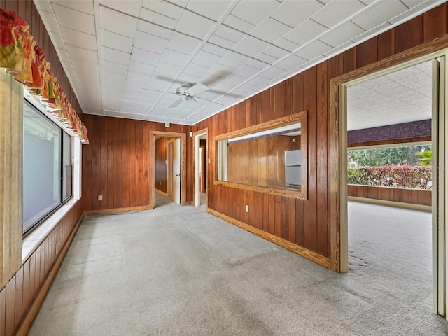 spare room featuring wood walls, carpet, and ceiling fan