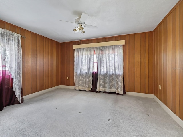 carpeted empty room with wood walls and ceiling fan