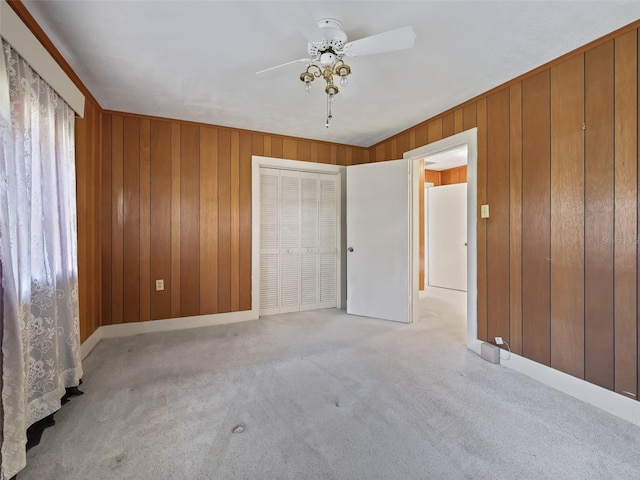 unfurnished room featuring wooden walls, ceiling fan, and carpet floors