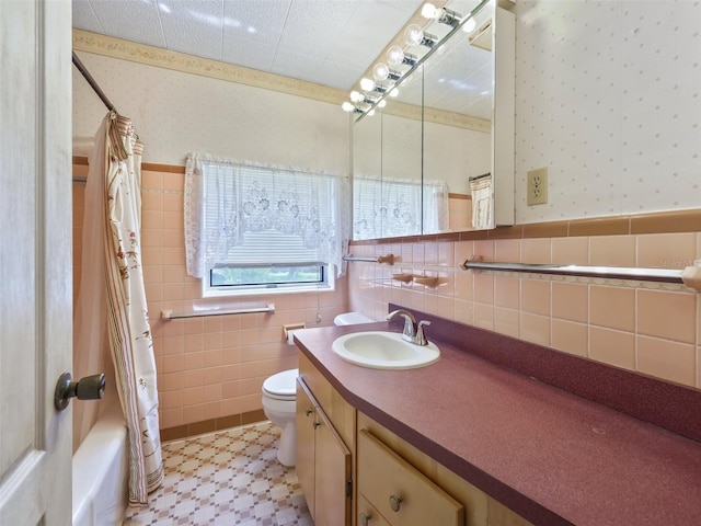 full bathroom with tile walls, large vanity, toilet, shower / bath combo with shower curtain, and tile flooring