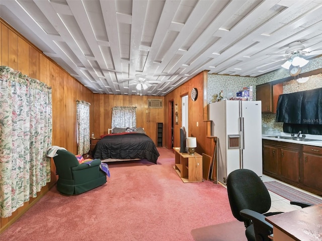 bedroom featuring white fridge, light carpet, wooden walls, a wall mounted air conditioner, and sink