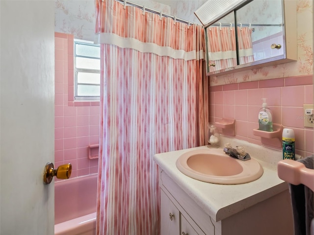 bathroom featuring backsplash, shower / bath combo with shower curtain, vanity, and tile walls