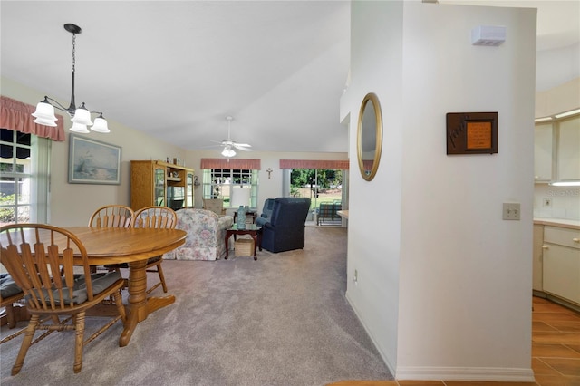 dining area featuring carpet, a wealth of natural light, vaulted ceiling, and ceiling fan with notable chandelier