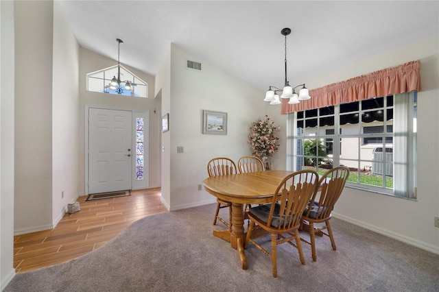 dining area with high vaulted ceiling, a notable chandelier, and light carpet