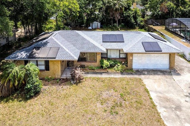 single story home with a front yard, solar panels, and a garage