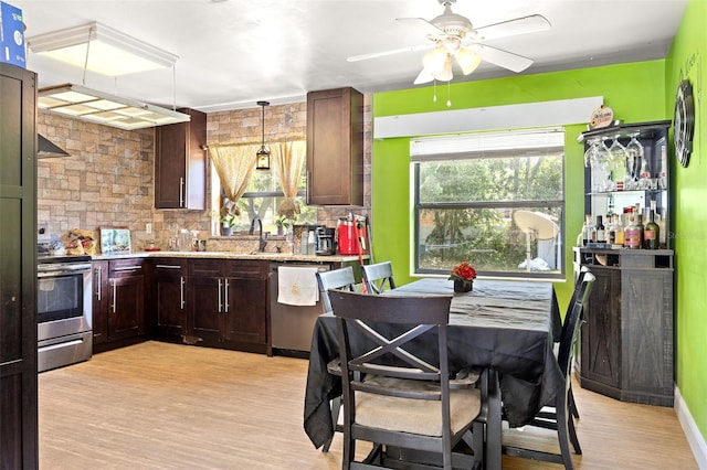 kitchen with appliances with stainless steel finishes, light hardwood / wood-style flooring, backsplash, ceiling fan, and hanging light fixtures