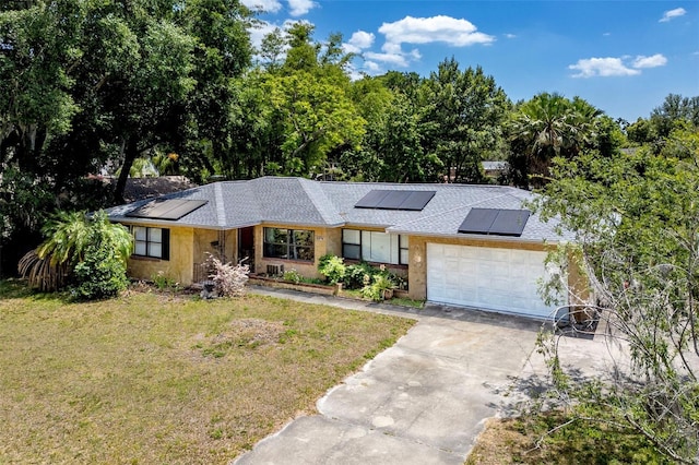 single story home with a garage, solar panels, and a front yard