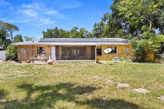 rear view of property with a yard, solar panels, and a sunroom