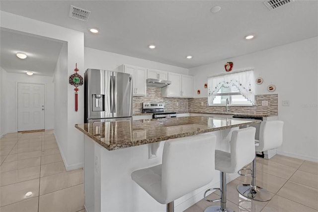 kitchen with appliances with stainless steel finishes, decorative backsplash, a center island, and white cabinets