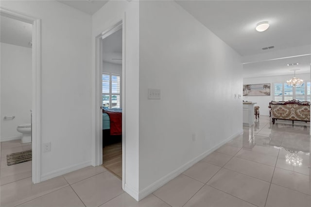 corridor with a chandelier, light tile patterned floors, and plenty of natural light