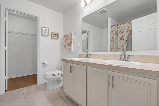 bathroom featuring vanity, a textured ceiling, tile patterned flooring, a shower with shower curtain, and toilet