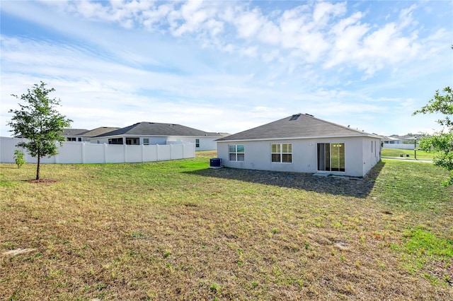 rear view of property with a yard and central AC