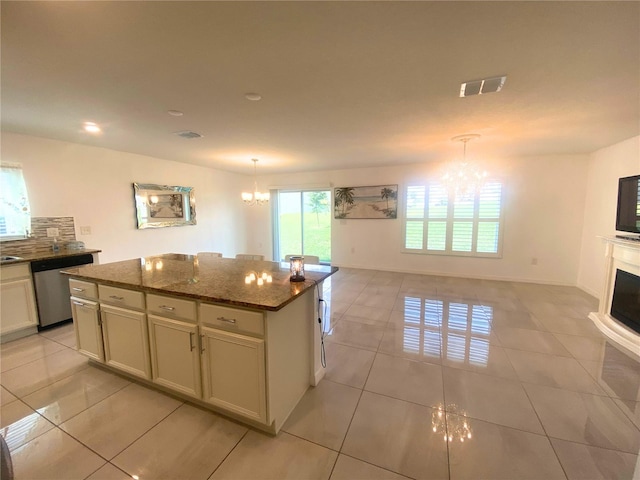 kitchen featuring dark stone counters, dishwasher, a center island, light tile patterned floors, and decorative light fixtures