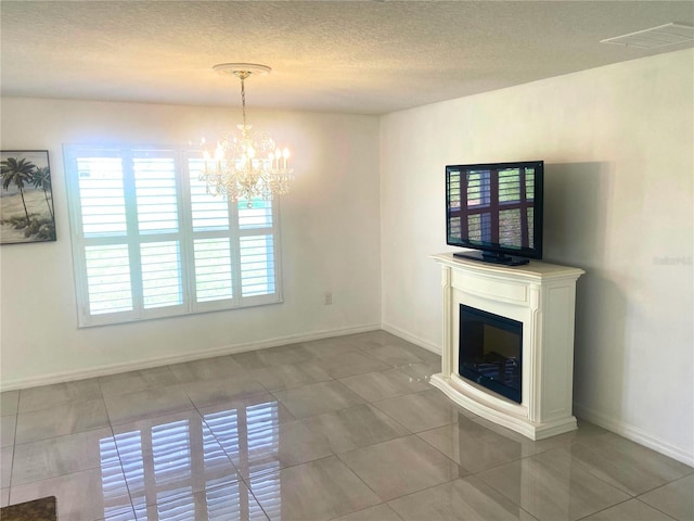 unfurnished living room featuring a chandelier, a textured ceiling, and tile patterned floors