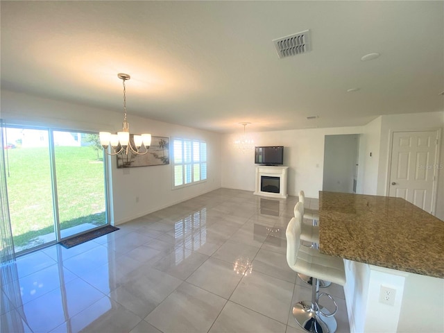 kitchen featuring dark stone countertops, a breakfast bar, light tile patterned floors, decorative light fixtures, and a chandelier