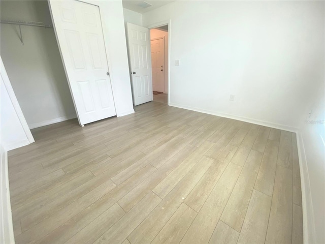 unfurnished bedroom with light hardwood / wood-style flooring and a closet