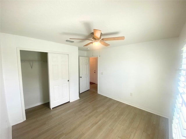 unfurnished bedroom with light wood-type flooring, ceiling fan, and a closet