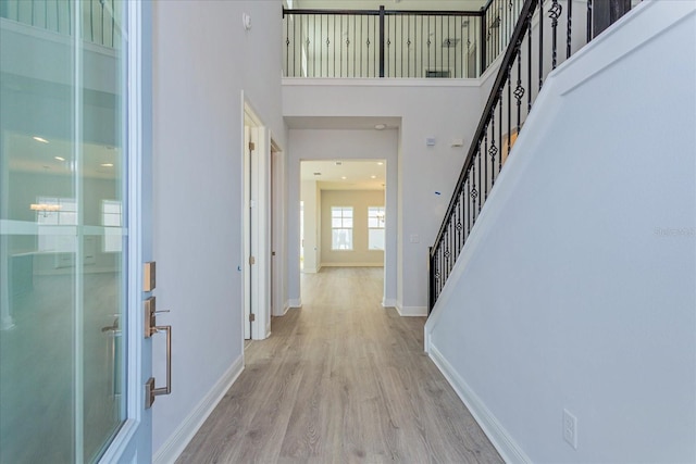 hallway featuring a towering ceiling and light hardwood / wood-style flooring