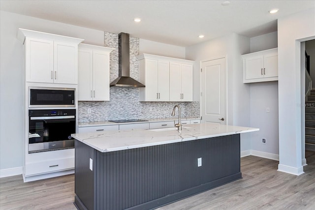 kitchen featuring a kitchen island with sink, wall chimney range hood, built in microwave, and oven