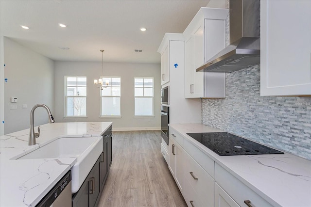 kitchen featuring white cabinets, decorative light fixtures, wall chimney exhaust hood, and appliances with stainless steel finishes