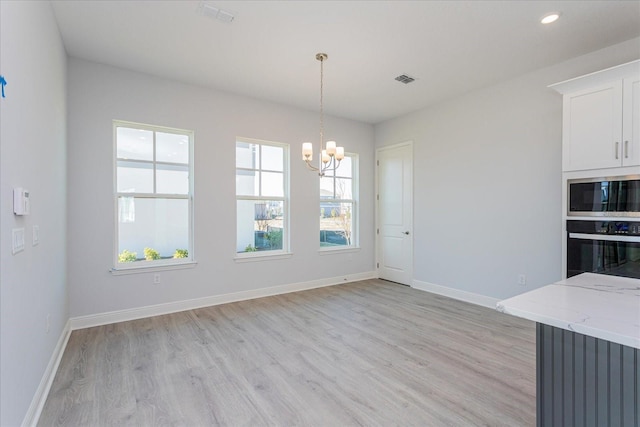 unfurnished dining area featuring a chandelier and light hardwood / wood-style floors