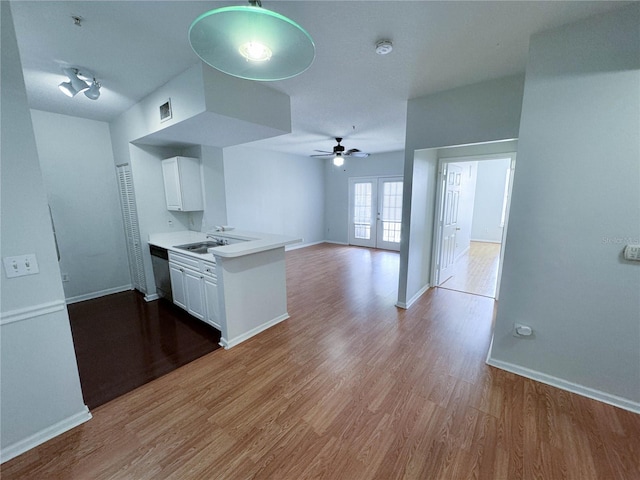 kitchen with ceiling fan, sink, white cabinetry, kitchen peninsula, and hardwood / wood-style flooring