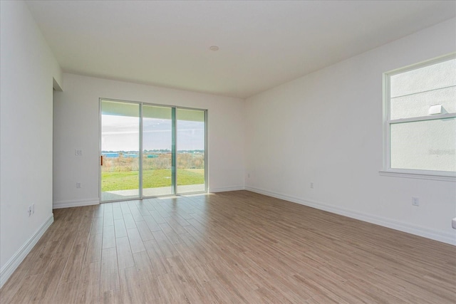 spare room featuring a wealth of natural light and light hardwood / wood-style floors