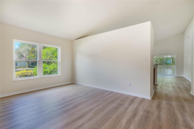 empty room featuring wood-type flooring and vaulted ceiling