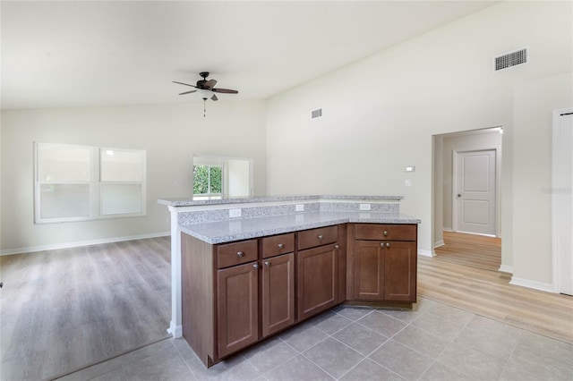 kitchen featuring high vaulted ceiling, light stone counters, ceiling fan, and light tile flooring