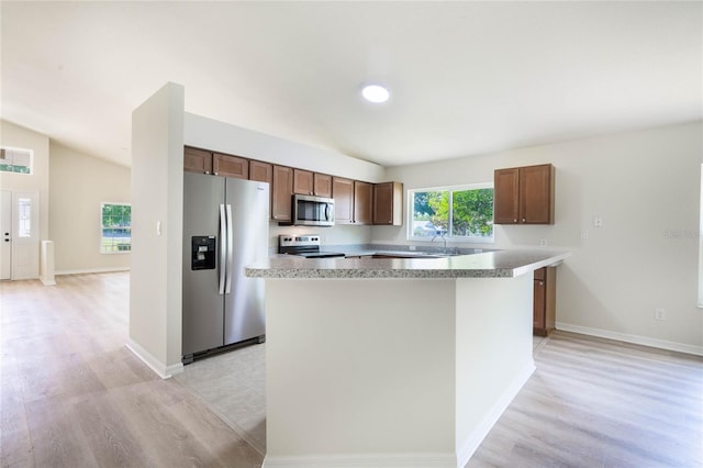 kitchen featuring light hardwood / wood-style flooring, stainless steel appliances, and vaulted ceiling