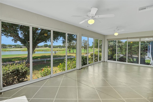 unfurnished sunroom with ceiling fan and a water view