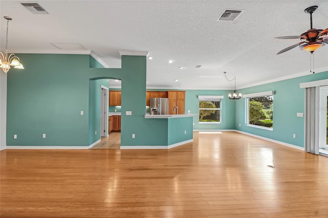 unfurnished living room with ornamental molding, light wood-type flooring, and a textured ceiling