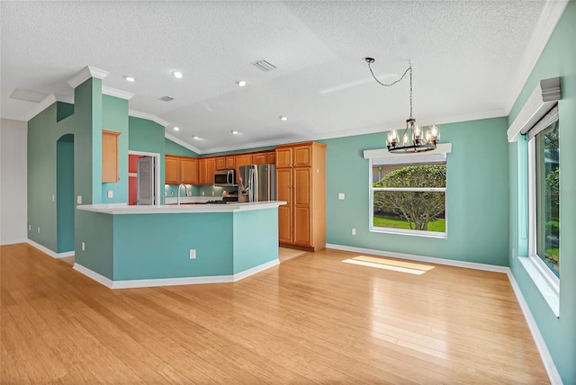 kitchen featuring decorative light fixtures, light wood-type flooring, crown molding, kitchen peninsula, and appliances with stainless steel finishes