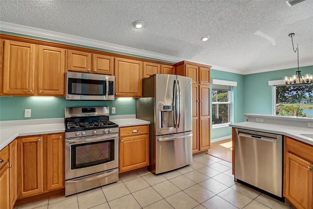 kitchen featuring a chandelier, ornamental molding, stainless steel appliances, light tile floors, and a textured ceiling