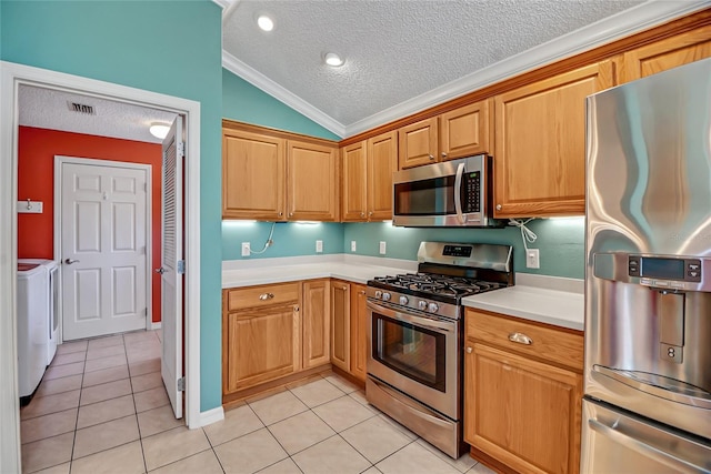 kitchen with light tile floors, stainless steel appliances, ornamental molding, vaulted ceiling, and separate washer and dryer