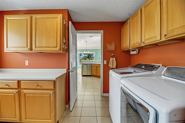 clothes washing area featuring cabinets, washer and dryer, a textured ceiling, an inviting chandelier, and light tile floors