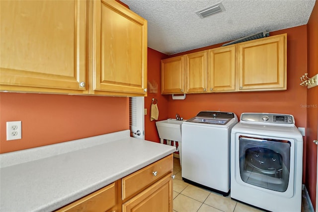 laundry area featuring cabinets, light tile floors, a textured ceiling, sink, and independent washer and dryer