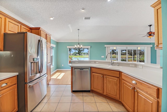 kitchen with sink, ceiling fan with notable chandelier, light tile flooring, hanging light fixtures, and stainless steel appliances