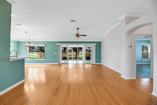 unfurnished living room featuring ceiling fan with notable chandelier, a textured ceiling, sink, light wood-type flooring, and ornamental molding